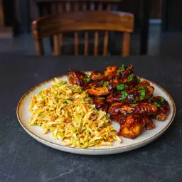 Pyszne skrzydełka z airfryer w sosie barbecue, podane z chrupiącą surówką z kapusty. Idealne na szybki obiad.