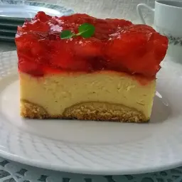 Pyszny sernik pieczony z galaretką na wierzchu, ozdobiony listkiem mięty. Idealny na deser.