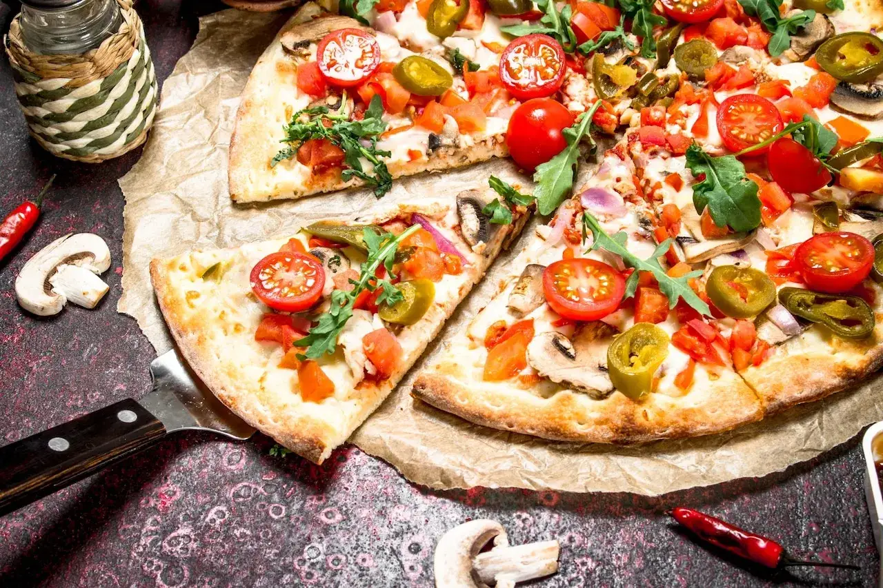Pyszna pizza na cienkim cieście z pomidorkami, jalapeno i rukolą, gotowa do podania.